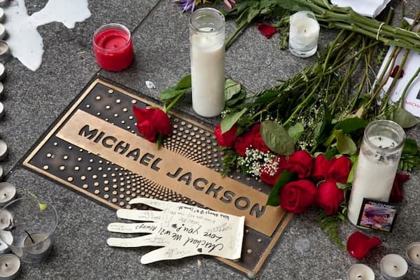 This shows candles, roses, and a white glove around an embedded plaque dedicated to Michael Jackson in the entry way of the Apollo