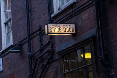 This is a night shot of the lighted sign marking the Apollo Theater's stage door.