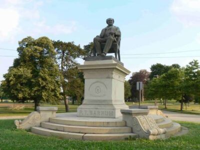 This is a monument recognizing Barnum, showing him sitting in a chair. It is located in Seaside Park, Bridgeport.
