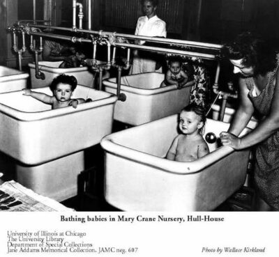 A black and white photograph of three babies in porcelain tubs being bathed ath Hull House