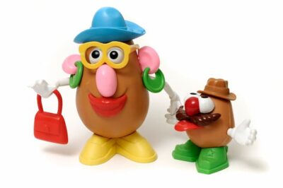 This image is of Mrs. Potato Head and  friend. She wears a blue hat, green earrings, and yellow shoes, and carries a red purse.