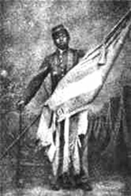 A young William H. Carney in dress uniform holds up for display the American flag. It is a black-and-white grainy photograph.