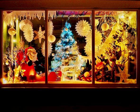 Santa, reindeer, and snowflakes on display in a store window, hoping people will come in to shop.