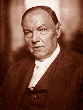 A sepia photo of an older Clarence Darrow. His eyes are bright; his skin shows age, He seems about to speak.