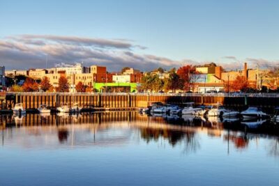 A beautiful color photo of Port Chester near the water. There are boats, and the buildings beyond reflect many different colors. 