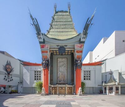 This is a color photograph showing the distinctive roofline of the TCL Chinese Theater on Hollywood Blvd. The roof  is green and appears to be thatched. The columns in front are bright orange.