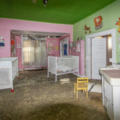This color photo shows a room with a couple of cribs and and a changing table--one of the several rooms from the home that were dedicated to the Birthing Center.