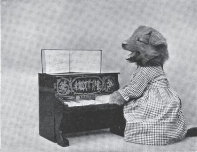The puppy, Barker, sits at a toy piano, accompanying himself as he sings. He is dressed in a gingham dress.