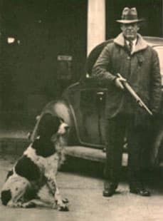 A candid photo of Jim with his owner about to go on a hunting trip. Van Arsdale holds a shotgun. Jim sits in front andto his side.