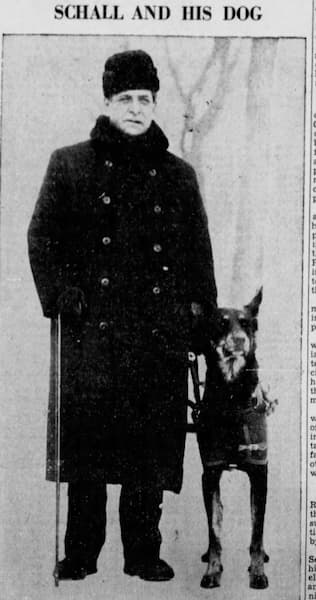 This is a newspaper photograph of Senator Schall, who eventually received Lux. He stands with Lux at his left side. He is well-dressed for winter weather.