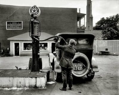 A black-and-white photo of a man adding gas at a Texaco Gas Station. 
