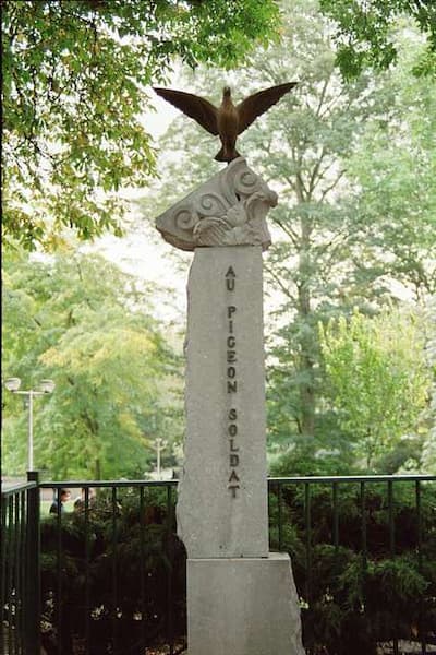 A pigeon rises above this monument to "Au Pigeon Soldat."