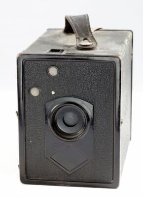 A photo of a black box camera. On the left side (hidden from view) is a handle for advancing the film. 