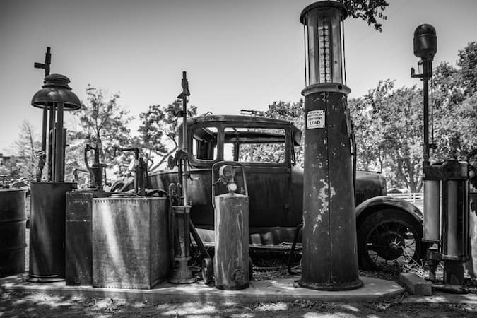This is a black-and-white photo of a Model T car parked by a gasoline pump that likely dates to 1910. istockphoto MWCphoto