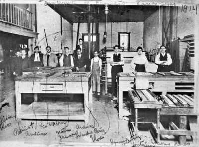 Jovita idar at a newspaper office, standing with others behind the printing presses.