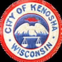 The patch shows a bird (a pelican?) holding scales of justice. The City of Kenosha is in blue. A red circle surrounds the exterior circle.