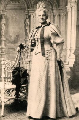 This is a photograph of Elizabeth Keckly dressed in her finery. Her hair is white and she carries a beautiful parasol.