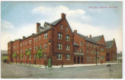 This is a color postcard photograph of Hull House. It is a 4-story red brick building sitting prominently on a corner.