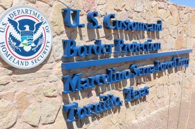 Sign on a stone wall reads: U.S. Customs and Border Protection, Marcelino Serna Port of Entry, Tornillo, Texas, with the U.S. Department of Homeland Security seal in the upper left, honoring the legacy of Marcelino Serna.