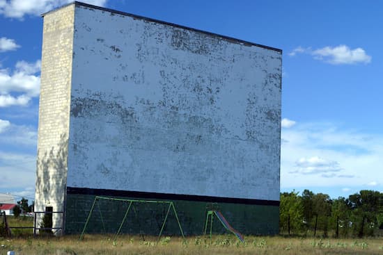 An abandoned drive-in theater screen with playground equipment underneath