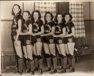 Black adn white photo of the All American Red Heads basketball team. The woman in the front is a full head taller than her team members!