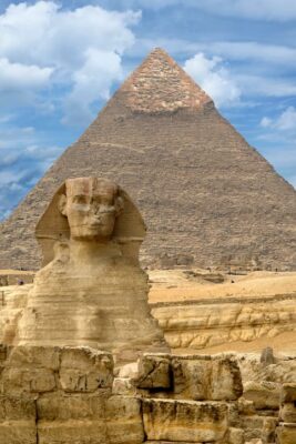 This is a color photograph that shows the colossal statue of the Graeat Sphinx and the even more impressive pyramid behind. istockphoto
