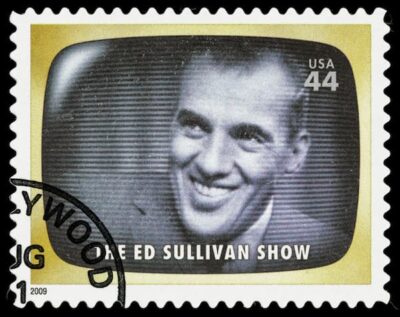 The 44 cent stamp shows the shape of a television and a very good photo of Ed Sullivan as if he were on the air.
