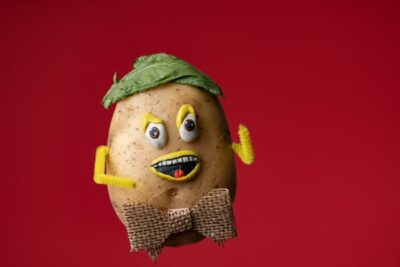He is made from a real potato; has pipe cleaner arms, sports a hat made from a leaf, and has hand-drawn eyes and a mouth. He also wears a bow tie.