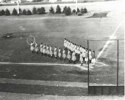 This is a newspaper photo of two teams  lining up in a V-formation before a game. The Star Spangled Banner would have been played at that time.