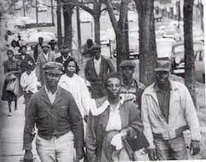 Broadside Beacon; black-and-white photo of men and women walking work. The photo shows at least 20 Black people walking in Montgomery