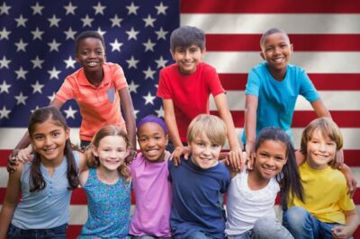 A group of nine children about 11-years-old standing in front of the American flag. They represent people of all backgrounds. istock wavebreakmedia