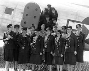 The nurses are standing in front of a plane ready to board to go home
